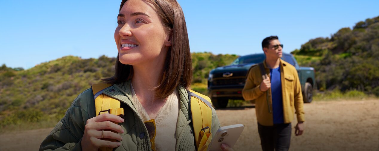 Un hombre y una mujer bajan de una pick up Chevrolet Cheyenne y miran el paisaje